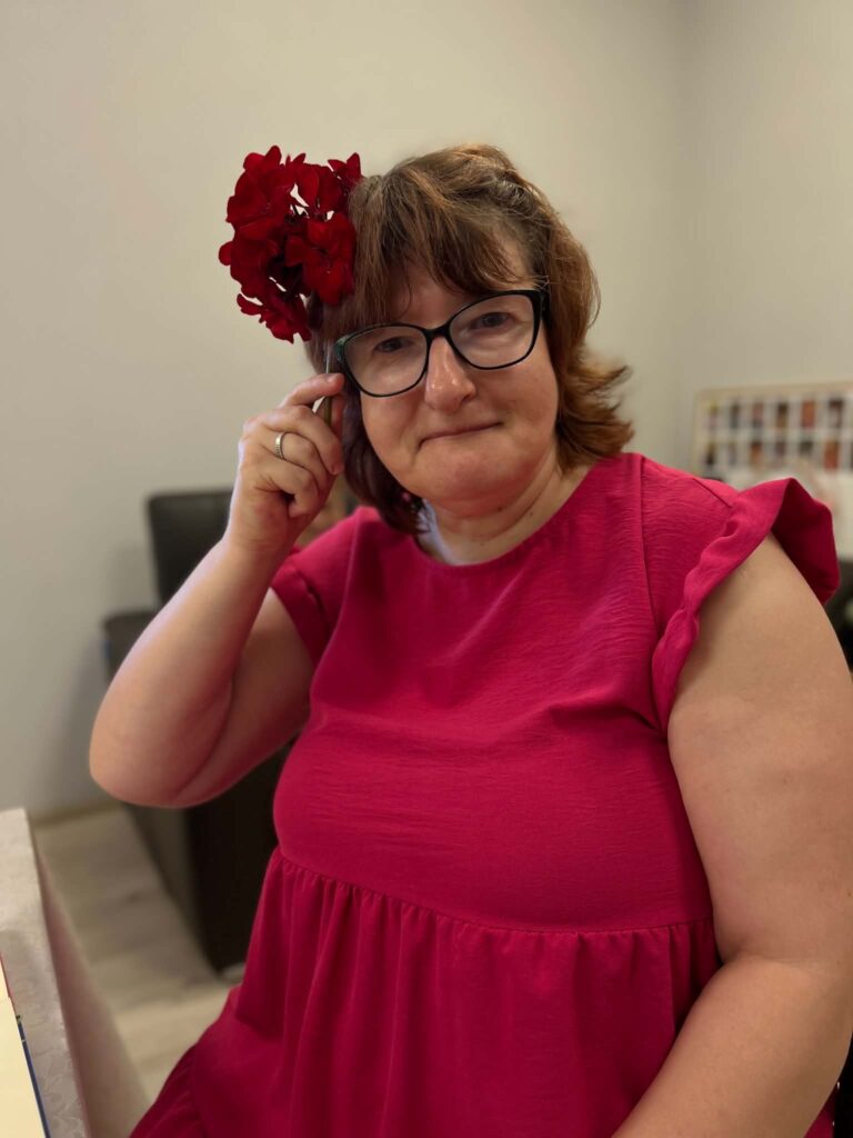 Dalyvė pozuoja su raudona gėle