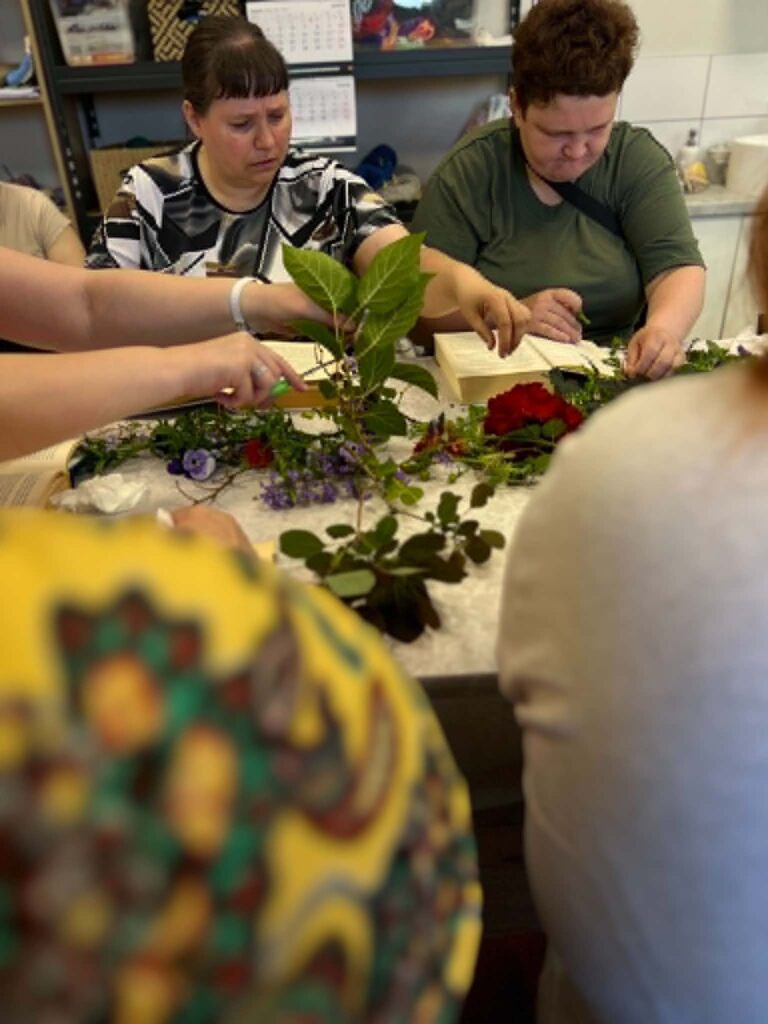 Dalyvės rūšiuoja surinktus augalus kūrybinei veiklai