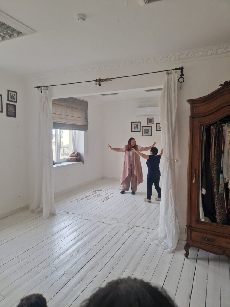 Two participants are acting by the curtains in the hall