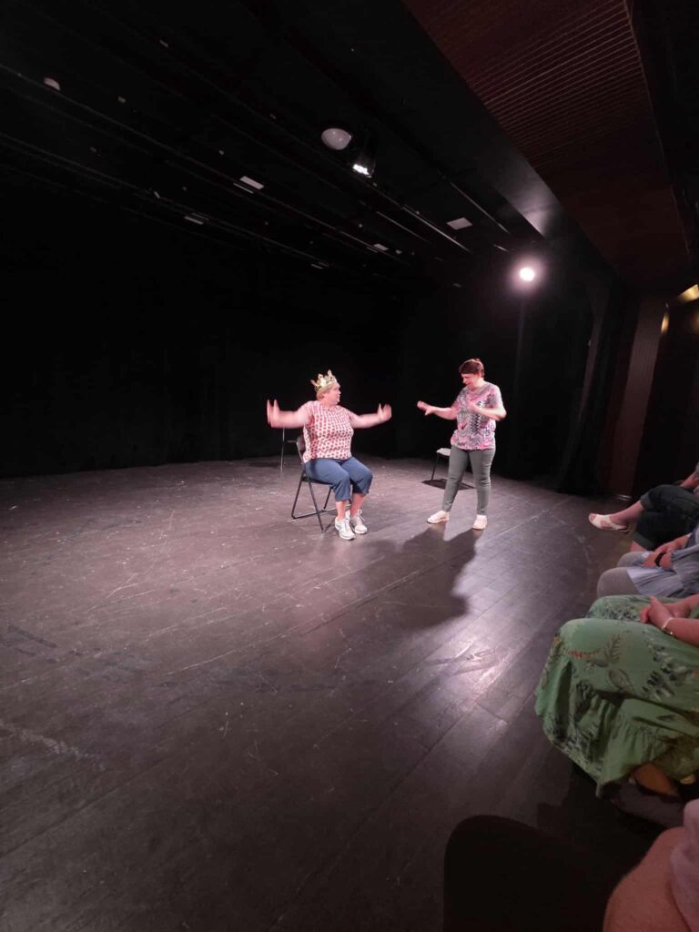 Two performers are acting on an open-air theatre stage