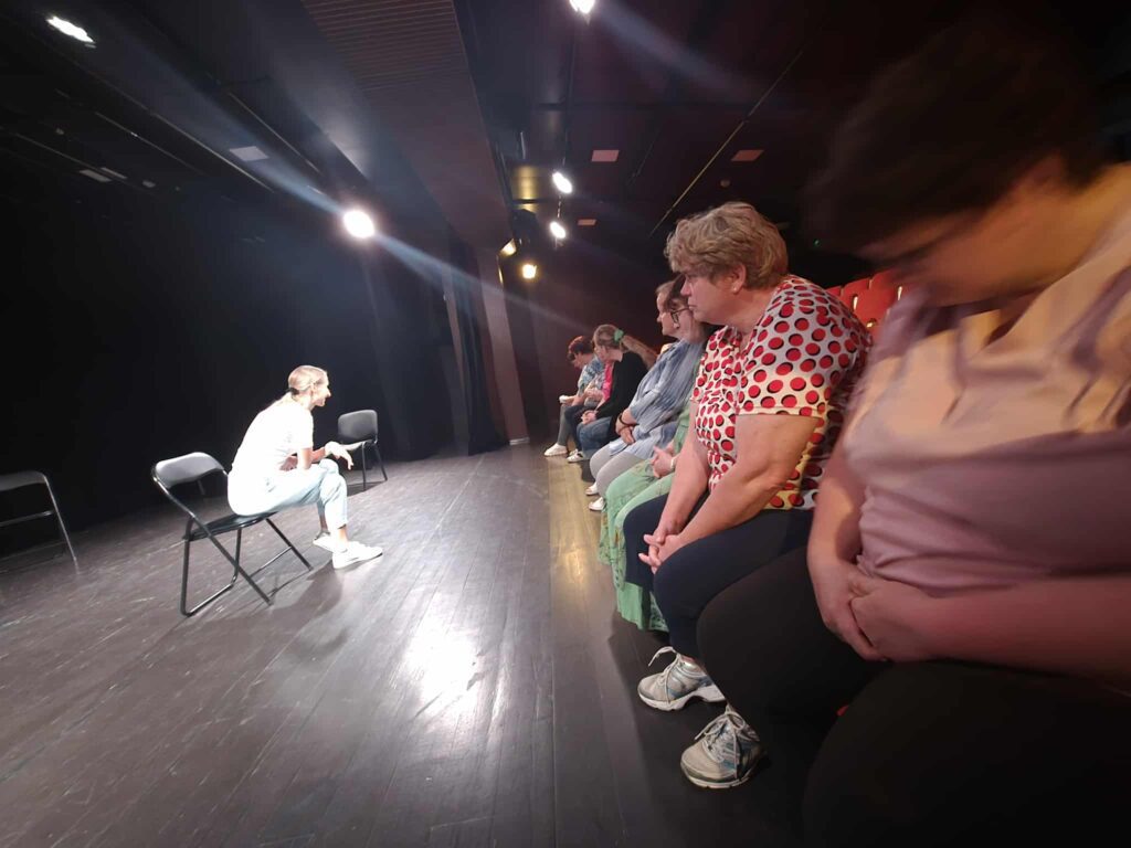 The participants are watching a theatre rehearsal on stage